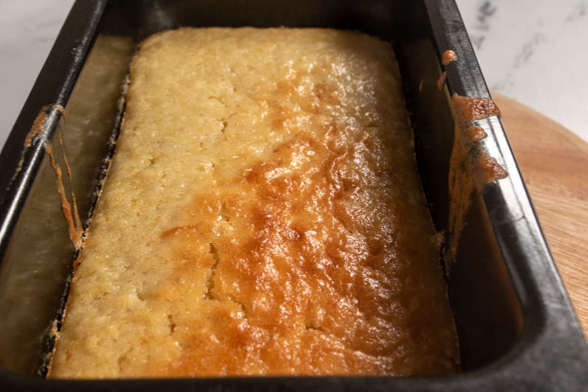 A single blackberry lemon loaf cake cooling down inside its tin.