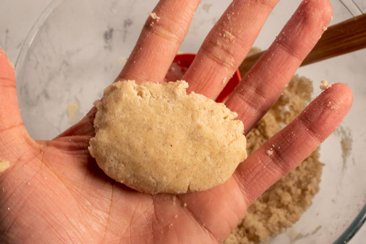 A moulded piece of biscuit batter in my hand, ready to be placed into the blueberries. 