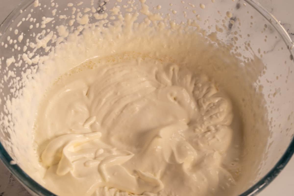 Vegan whipped cream inside a large bowl after being mixed with a hand mixer. 