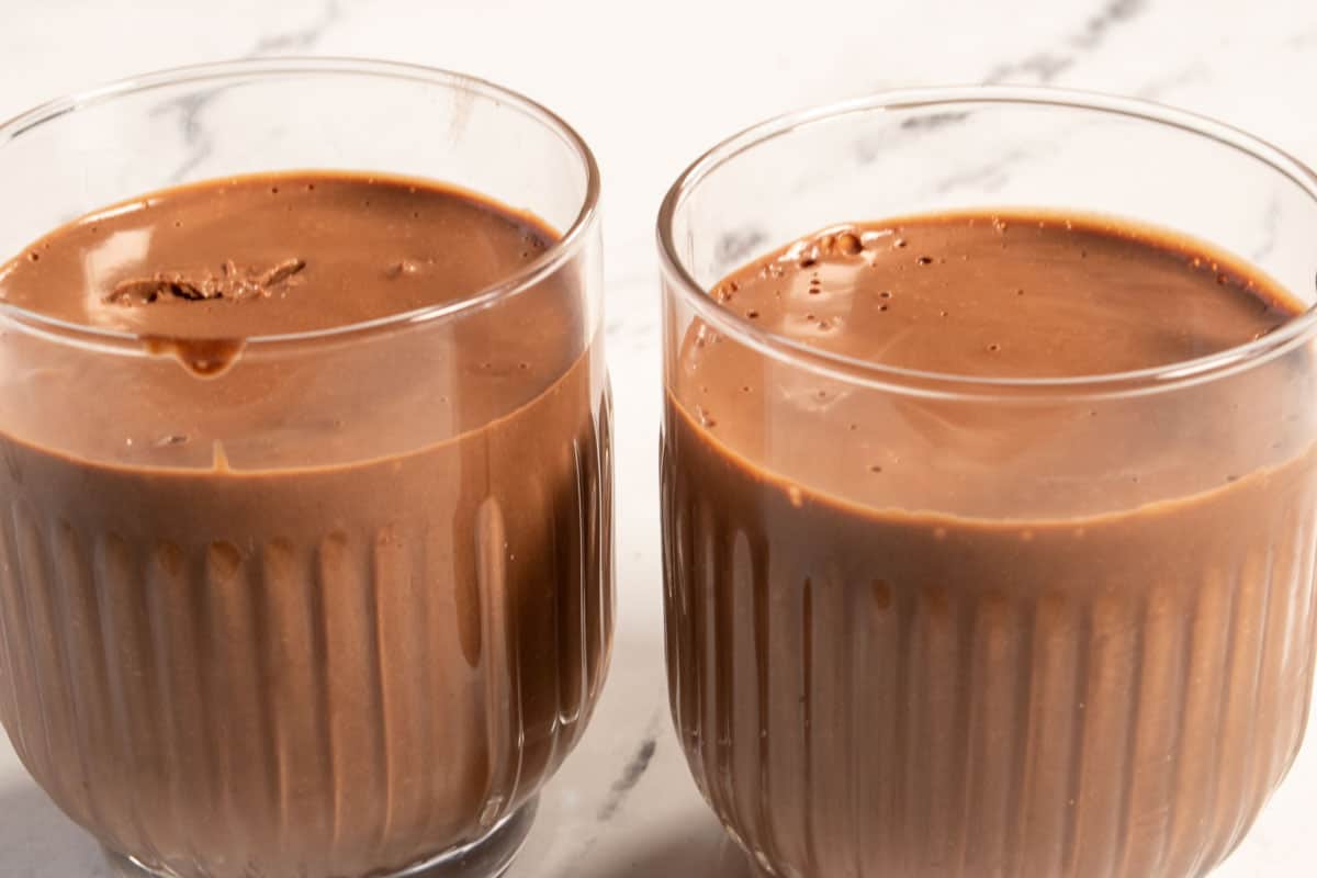Thickened vegan chocolate mousse inside two dessert glasses.