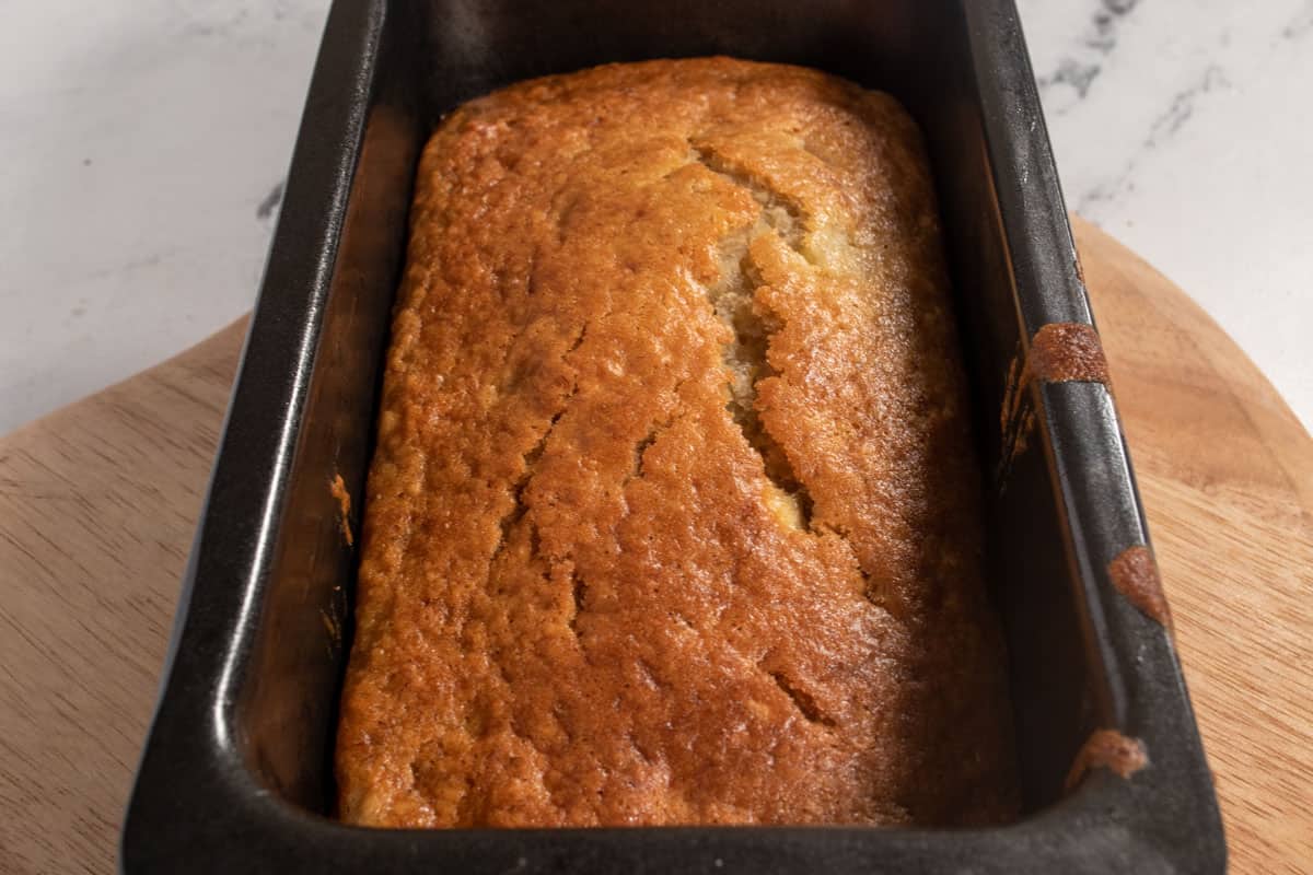 A baked banana cake loaf inside its tin after coming out of the oven. 