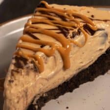 A creamy slice of vegan peanut butter pie on a serving plate with melted peanut butter drizzled on top.