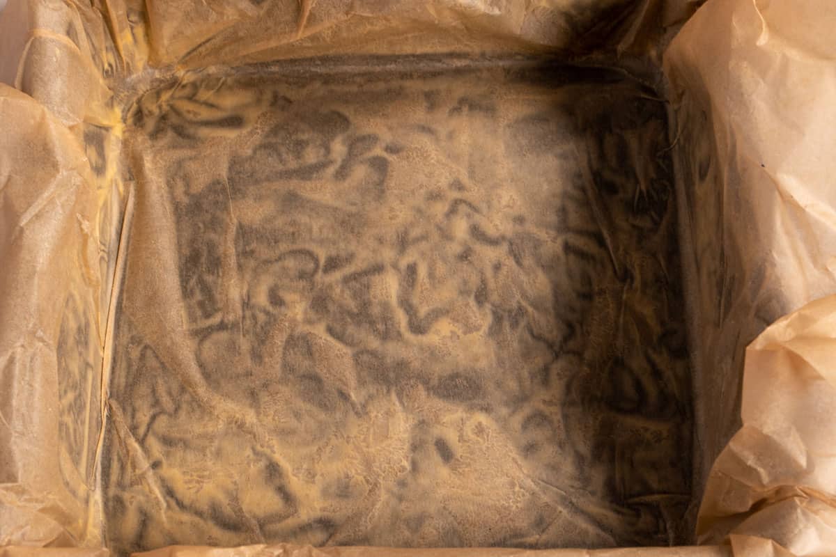 A large, square baking tin lined with parchment paper. 