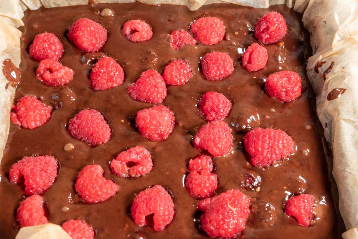 The chocolate mixture has been poured into the pan and topped with extra raspberries. 