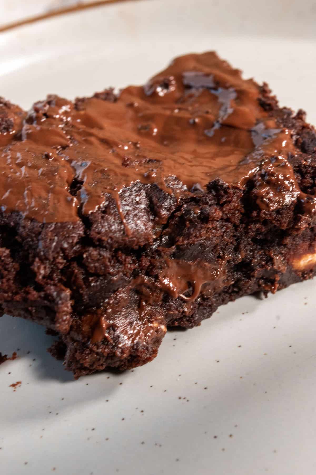 A moist, chocolatey piece of brownie sitting on a white serving platter.