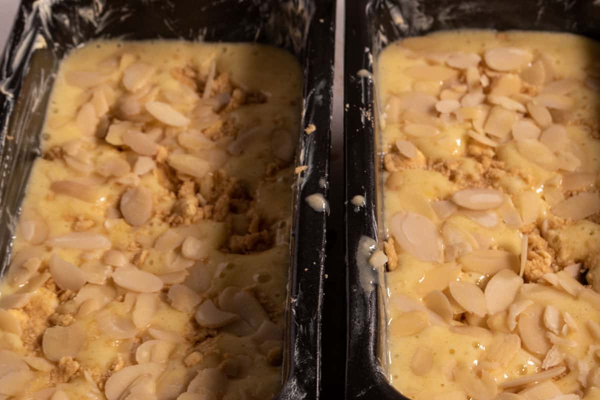 The cake batter has been poured into the two tins. The batter has been topped with the streusel and flaked almonds. 