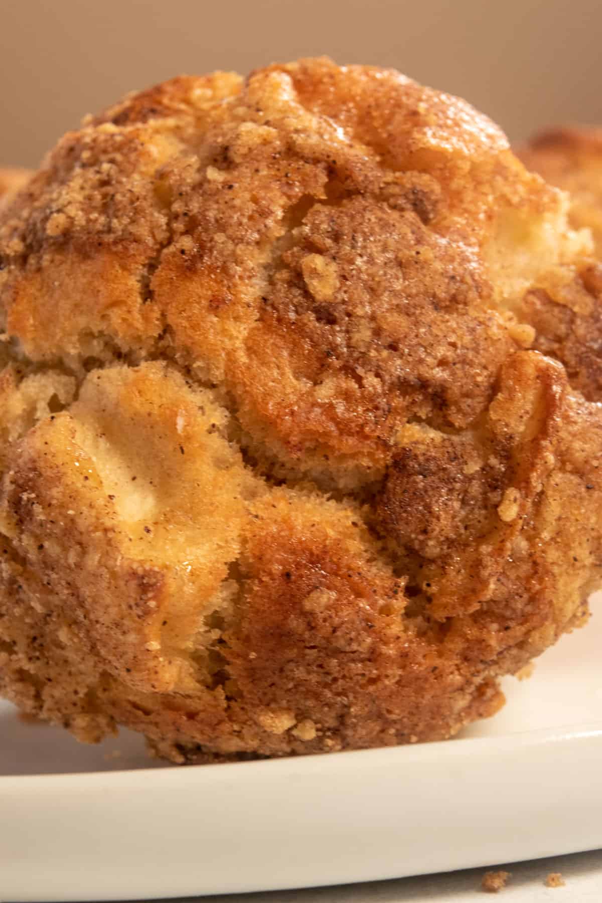 A larger apple muffin has been tipped onto its side. It looks very crumbly. 
