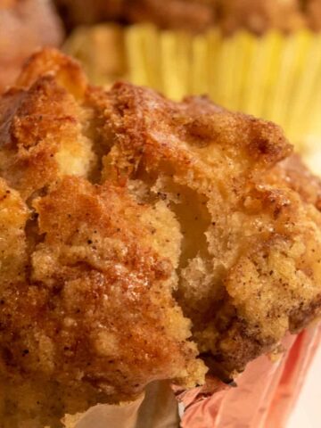 A golden brown and crumbly apple muffin cooling down close up to the camera.
