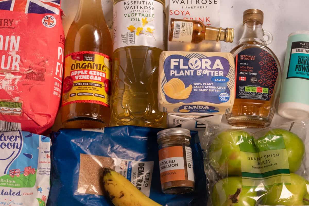 The recipe ingredients which are needed to make my vegan apple cinnamon muffins laid out over a white, marble background.