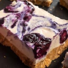 A large, creamy slice of blueberry cheesecake on a large slate board.