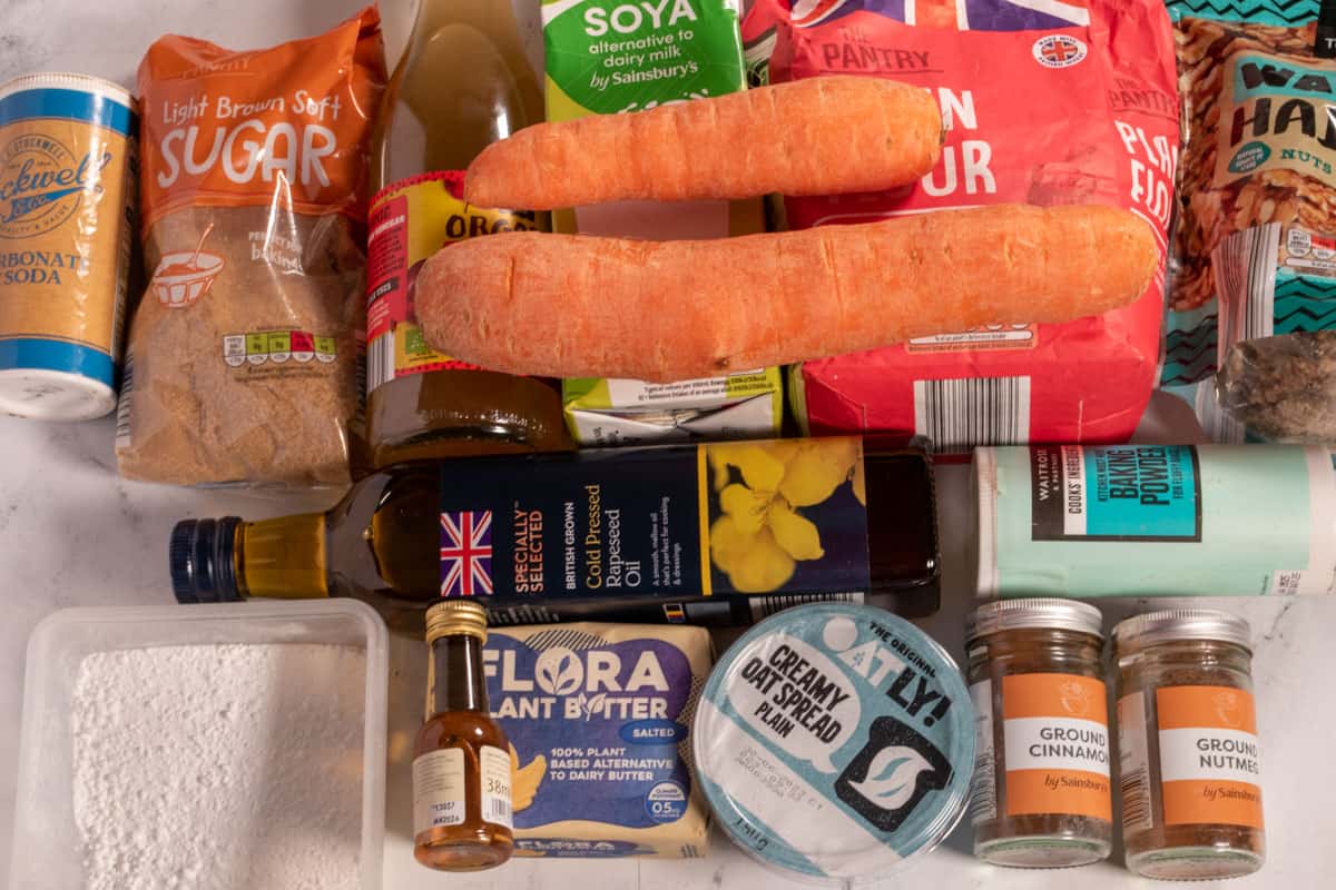 The recipe ingredients that are required for my vegan carrot cake bars, laid out over a white, marble background. 