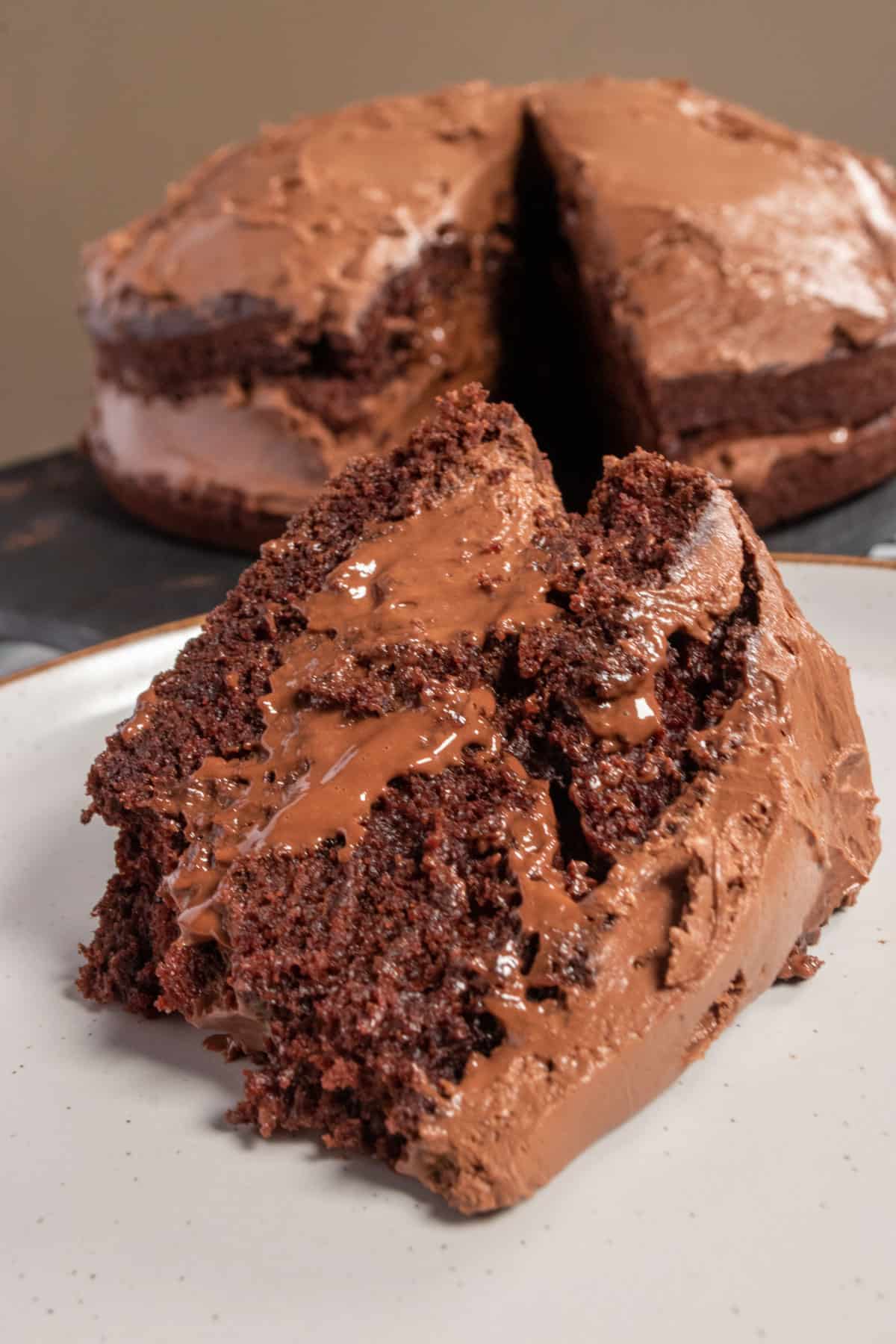 A chunky slice of vegan chocolate mousse cake. The rest of the cake is in the background. 
