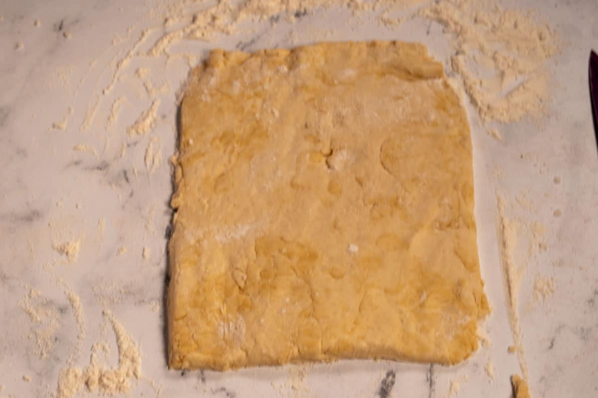 The dough is rolled out and sliced into a rectangular shape. 