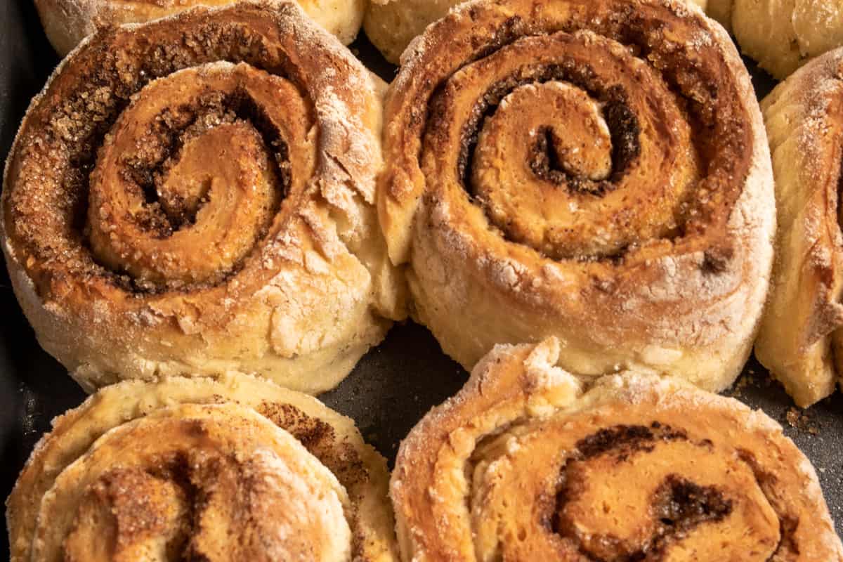 Baked, hot, golden brown cinnamon rolls just after coming out from the oven. 