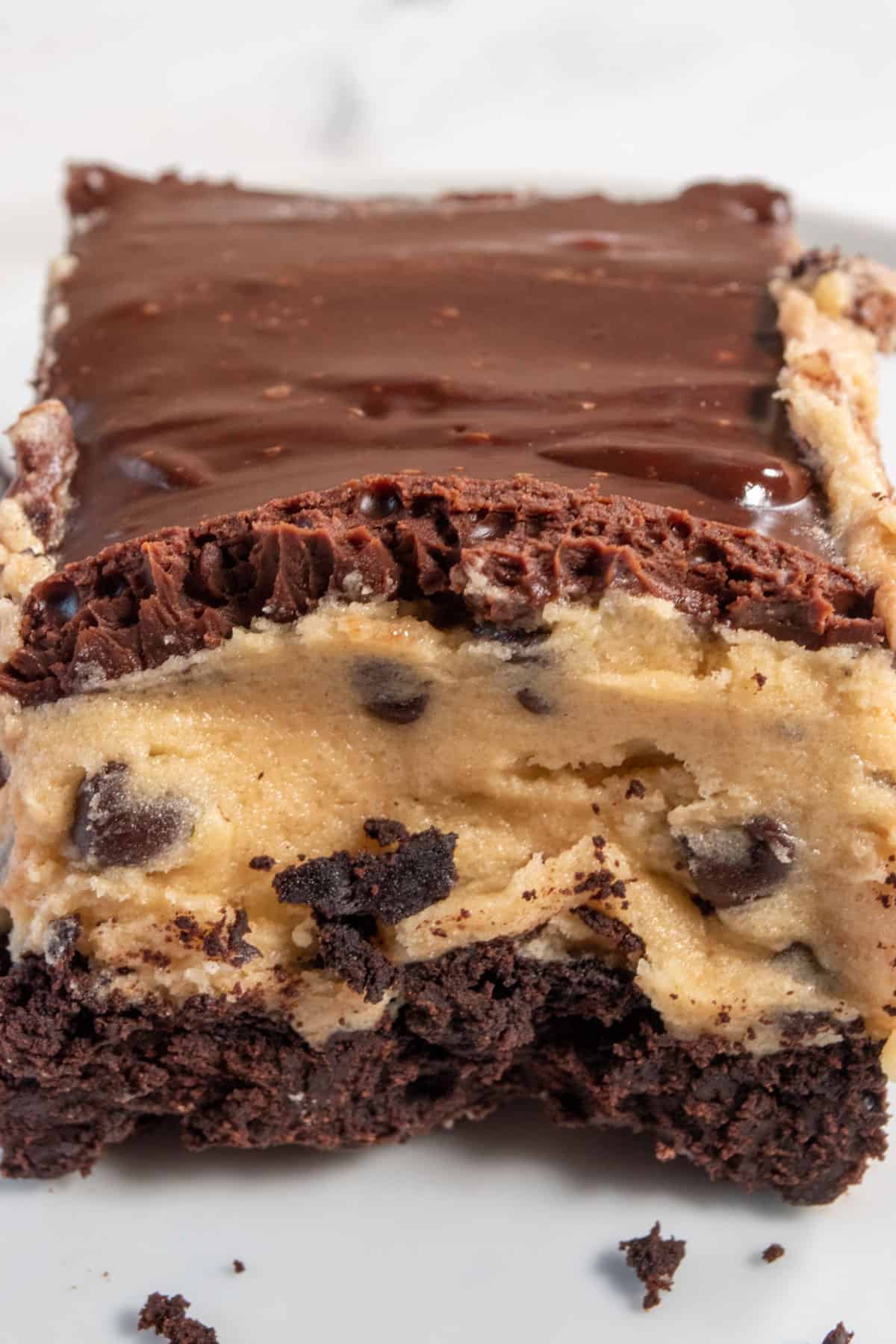 A  thick slice of cookie dough filling with chocolate chips. The chocolate topping is silky smooth. 