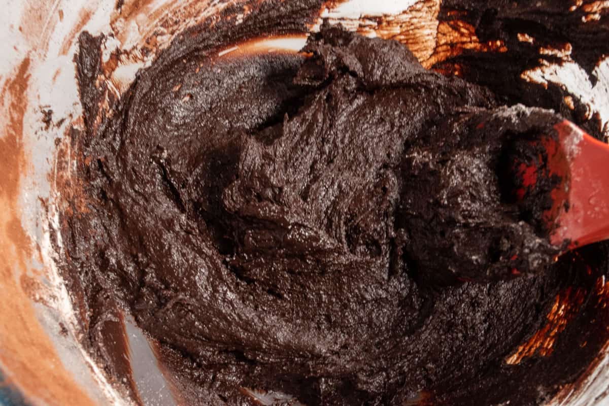 The brownie batter for the base being mixed inside a large bowl. 