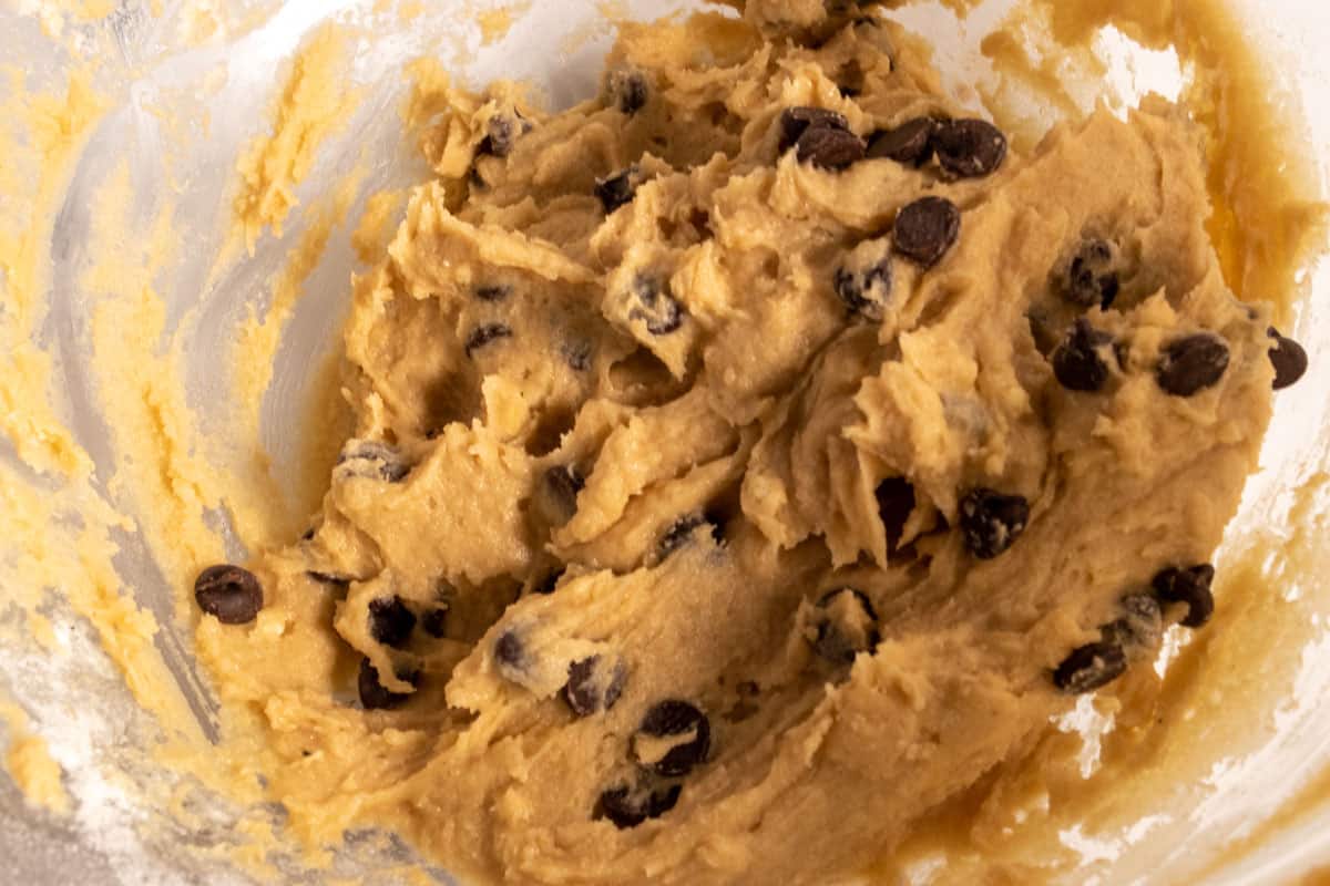 The cookie dough batter has been made inside another bowl. It is full of chocolate chips. 