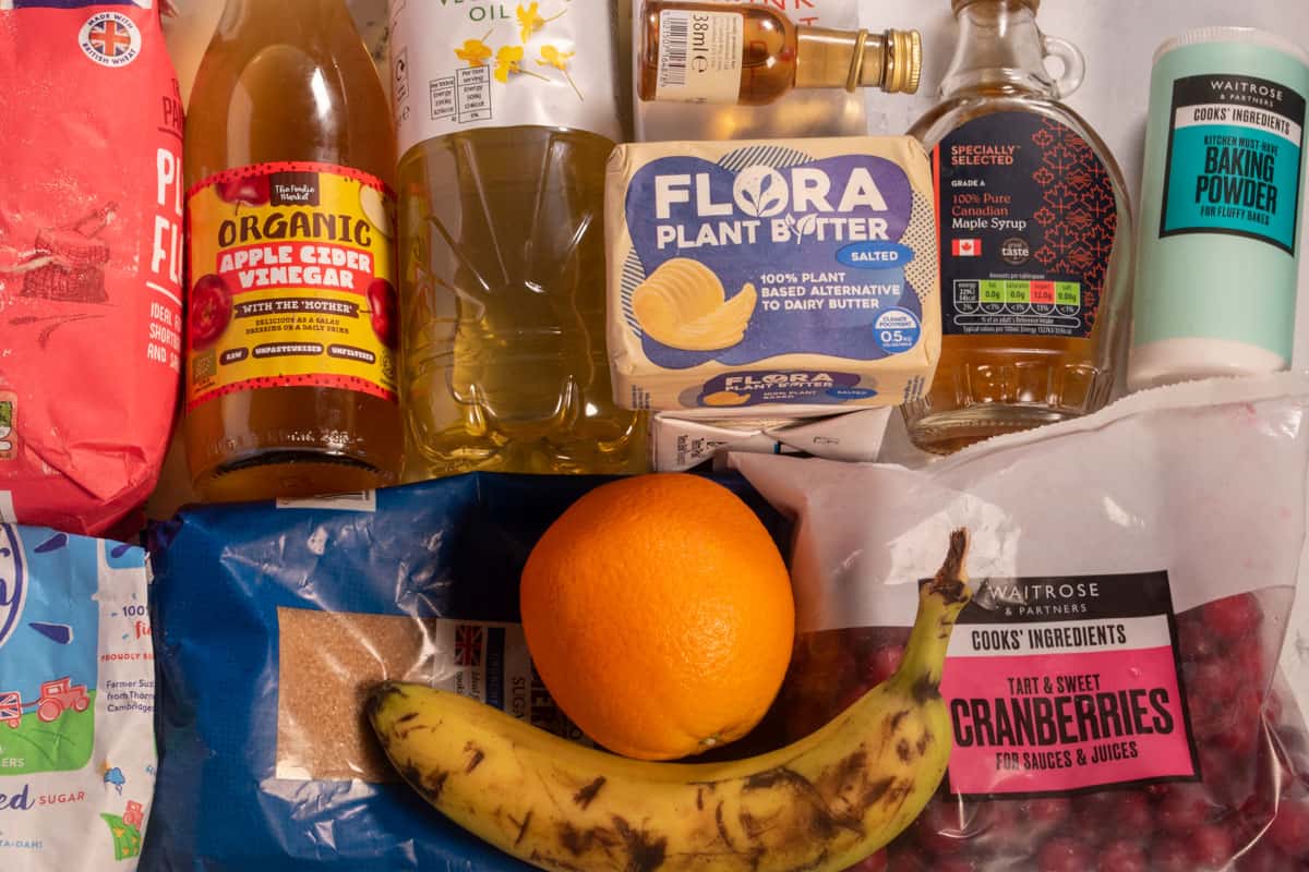 The ingredients that you will need to make my cranberry orange muffins laid out over a white, marble background.
