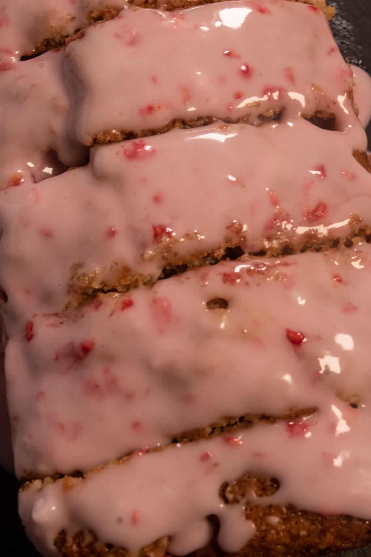 A zoomed in shot of my vegan raspberry cake. The slices are thick and topped with bright pink glaze. 