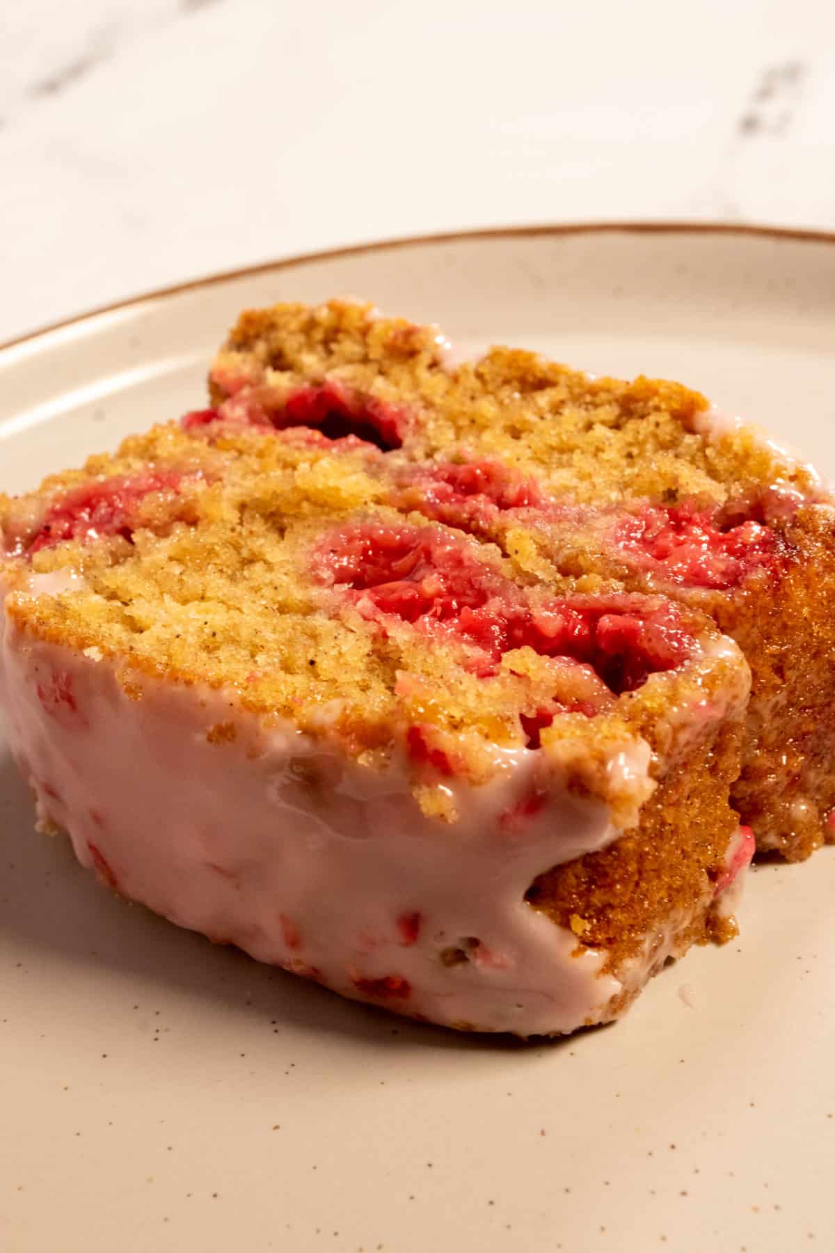 A golden, thick slice of raspberry cake which is filled with juicy raspberries. 