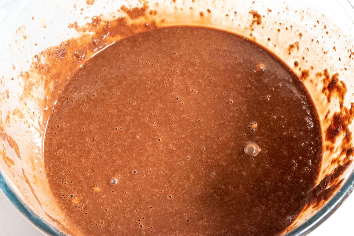 Runny chocolate cake batter inside a large mixing bowl. 