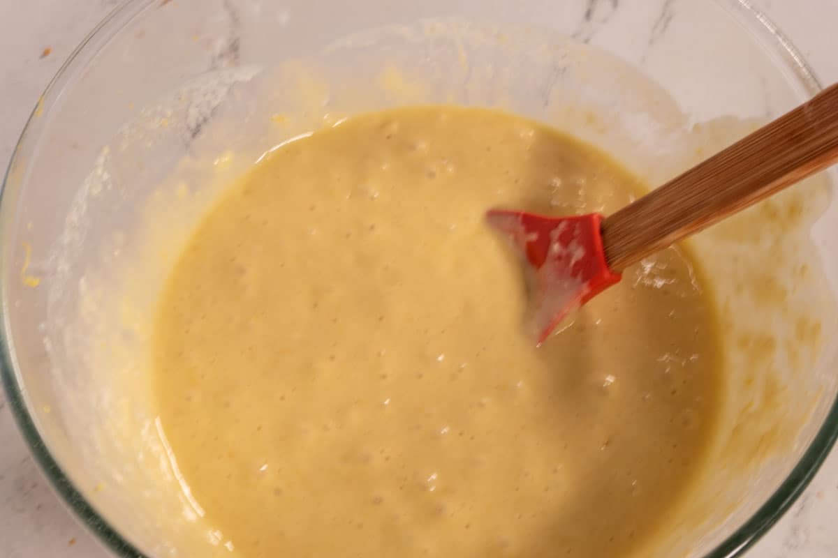 A smooth lemon cake batter folded inside a large bowl. 