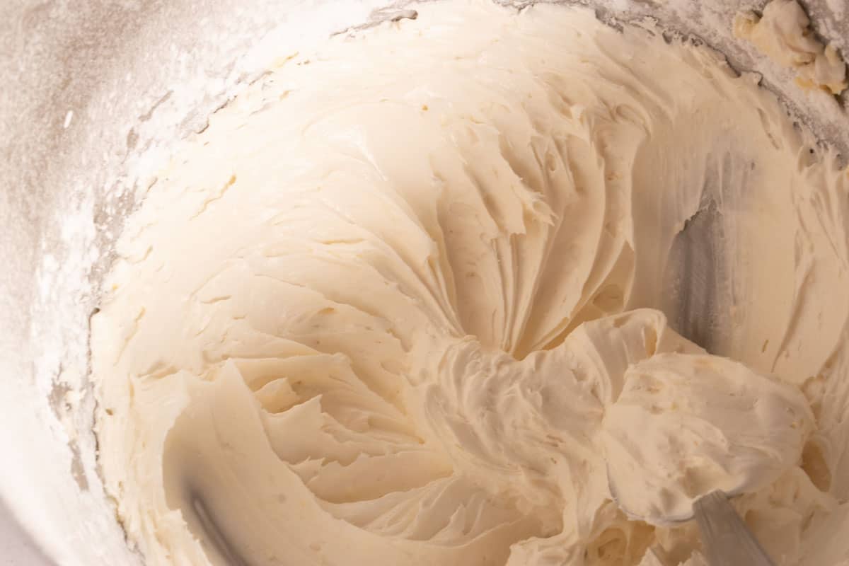 The lemon cream cheese frosting being made inside a large stand mixer. 