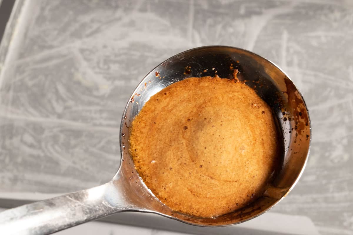 Baking powder has been added to the melted sugar. It has become a lighter brown and frothy.