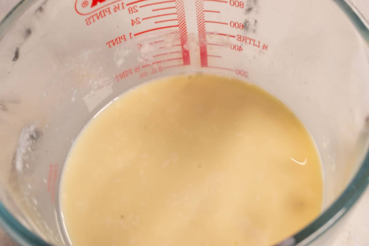 Vegan buttermilk curdling inside a pyrex jug.