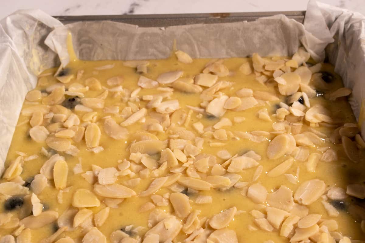 The almond cake batter has been poured into the prepared tin and topped with flaked almonds.