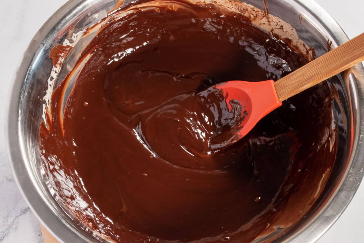 The melted chocolate for the topping is inside a large metal bowl. 