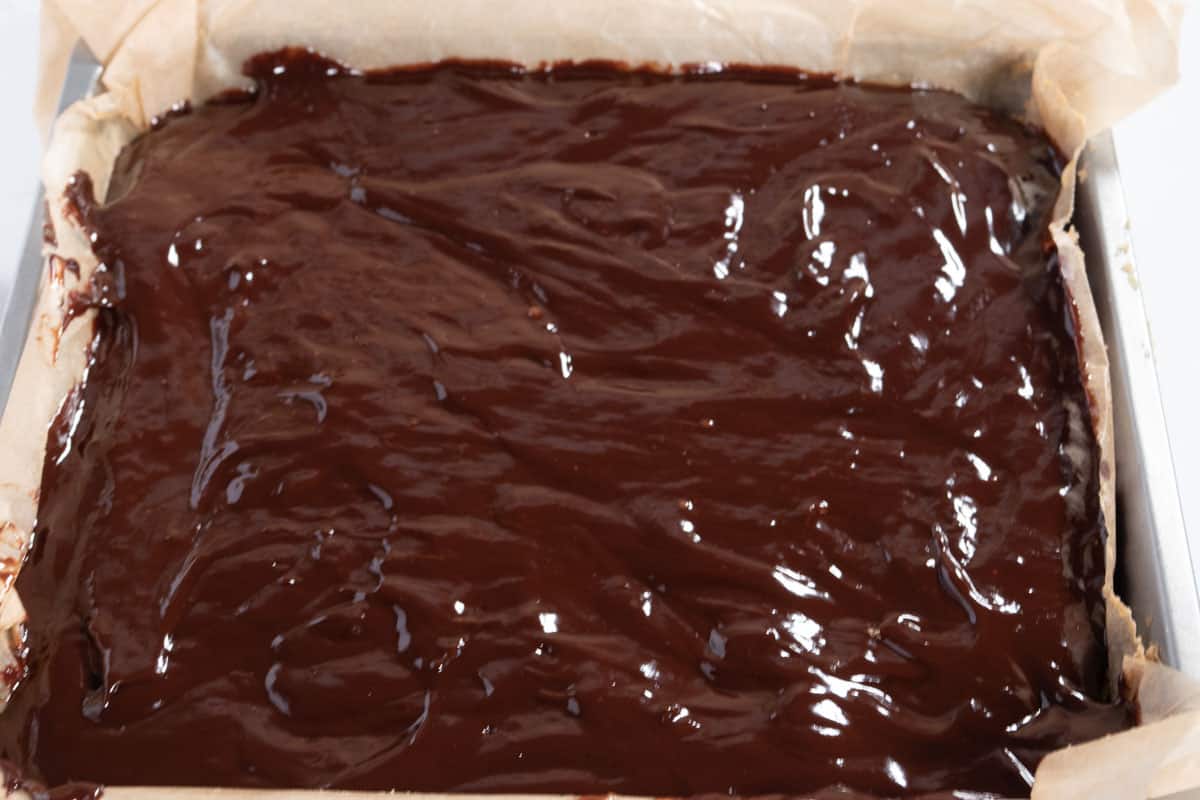 The chocolate has been poured over the caramel to form the final layer.