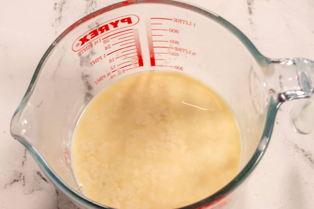 Vegan buttermilk curdling inside a large jug. 