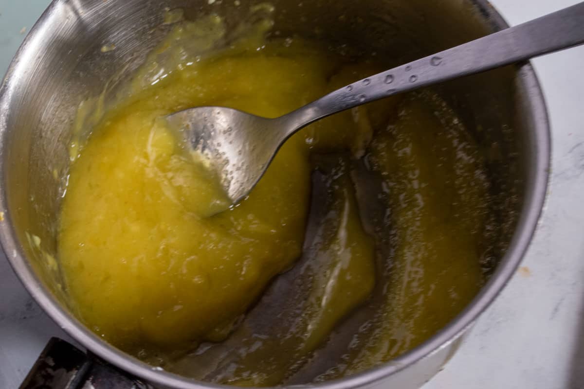 The lemon curd being made inside a small pan.