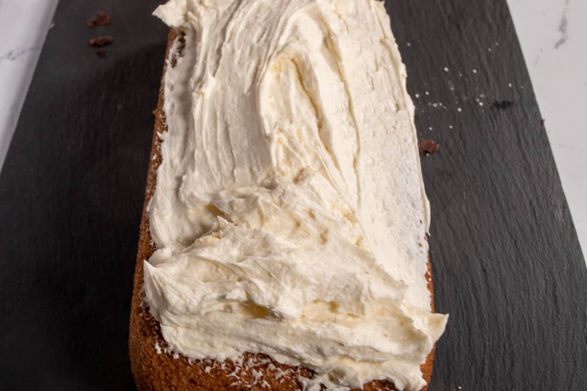 A layer of buttercream frosting has been spread onto one of the cakes.