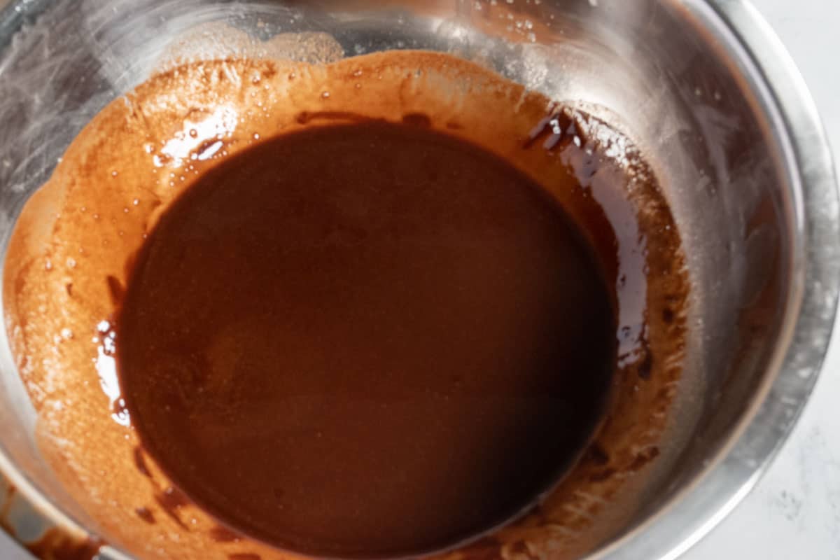 The butter chocolate mixture inside a metal bowl just after being melted. 