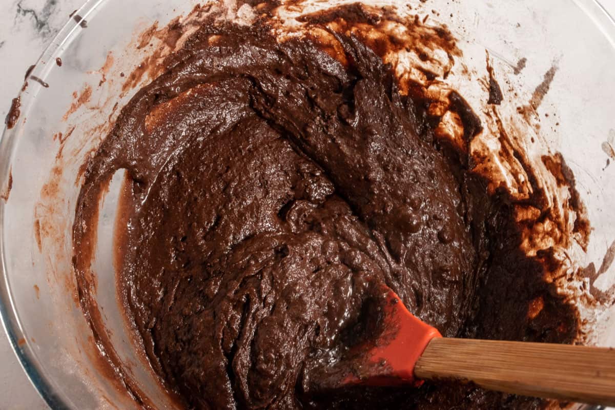 The vegan chocolate mud cake batter being folded with a spoon.