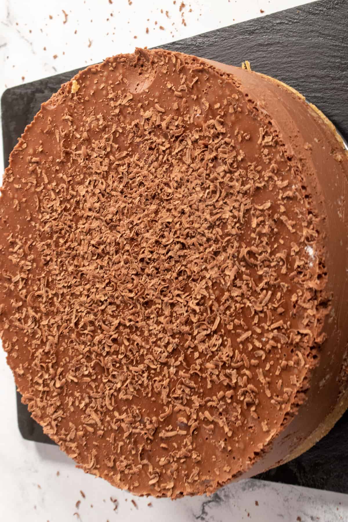 A whole chocolate cheesecake, topped with dairy free chocolate shavings.