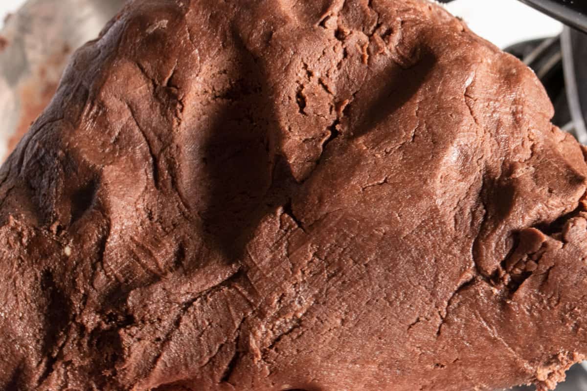 A large ball of chocolate cookie dough being held upwards.