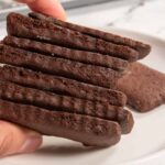 A stack of vegan chocolate wafer cookies being held in a hand.