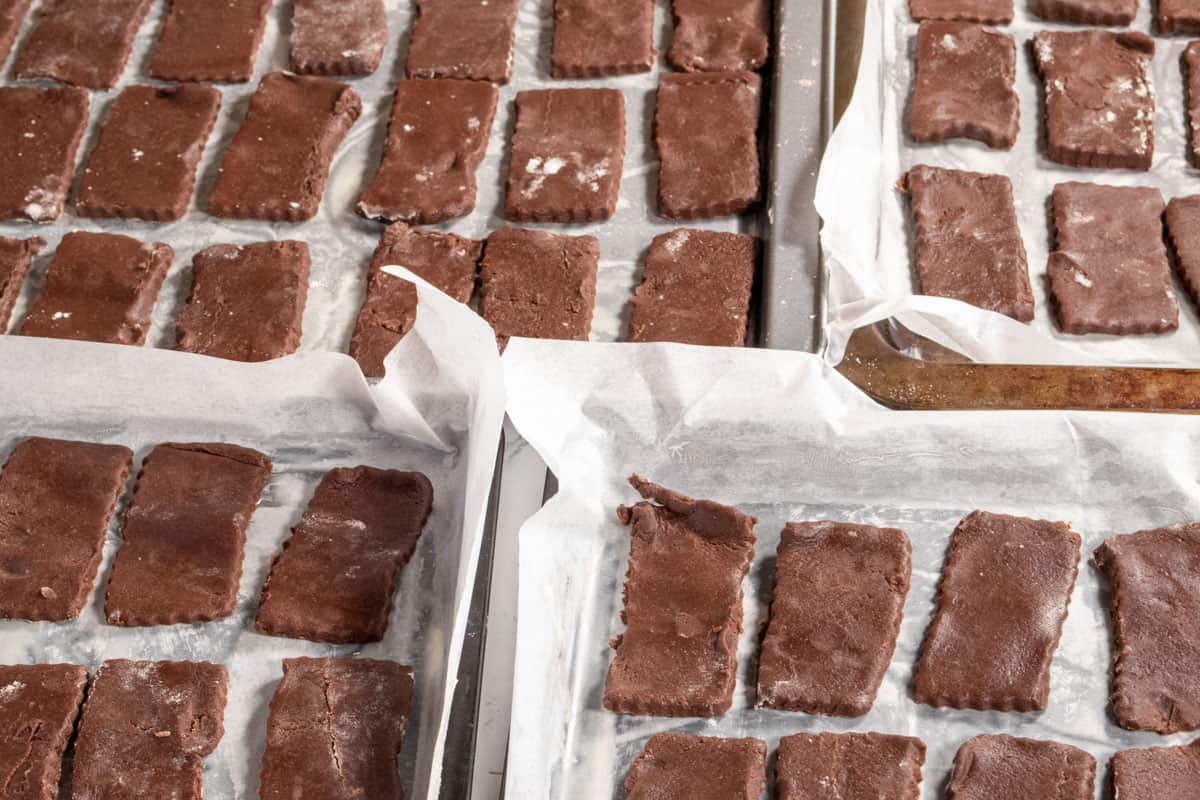 The cookies have been placed onto many lined baking trays and are ready to be baked. 