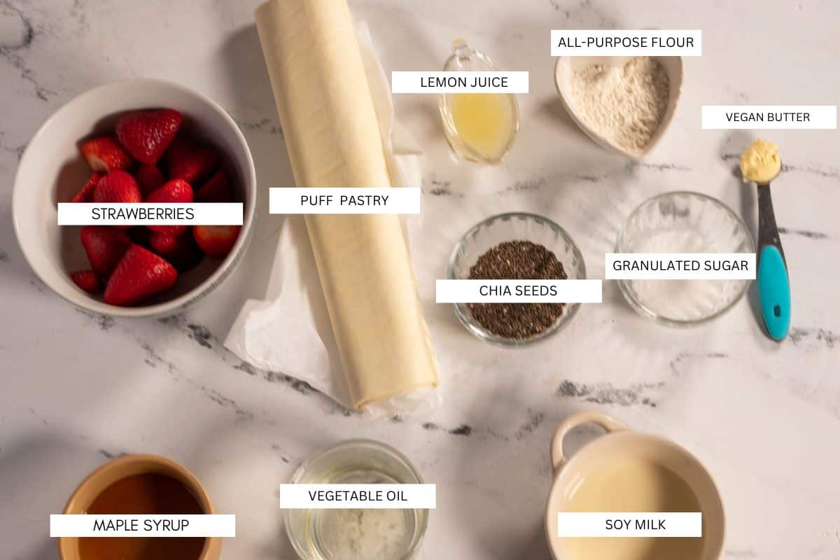 The ten ingredients that are needed to make vegan Danish pastries laid out neatly over a white marble background. 