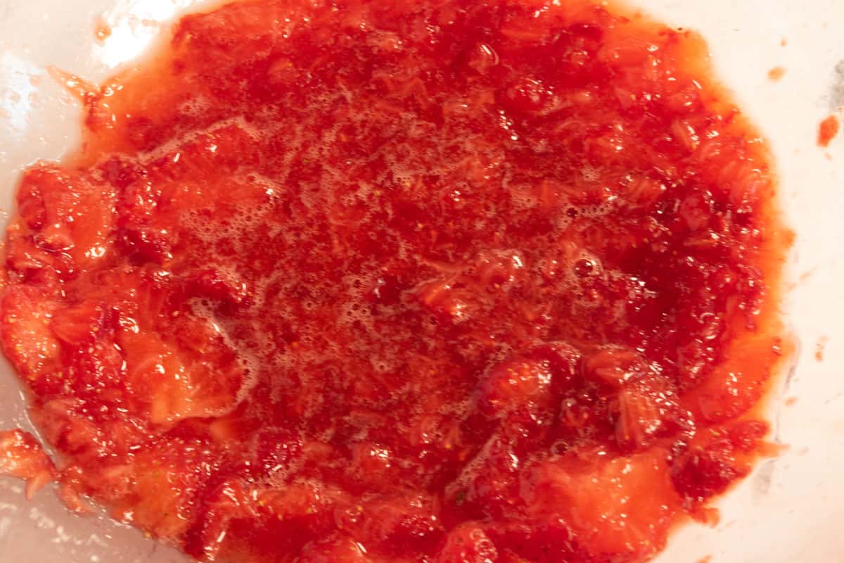 Strawberries mashed inside a large bowl.