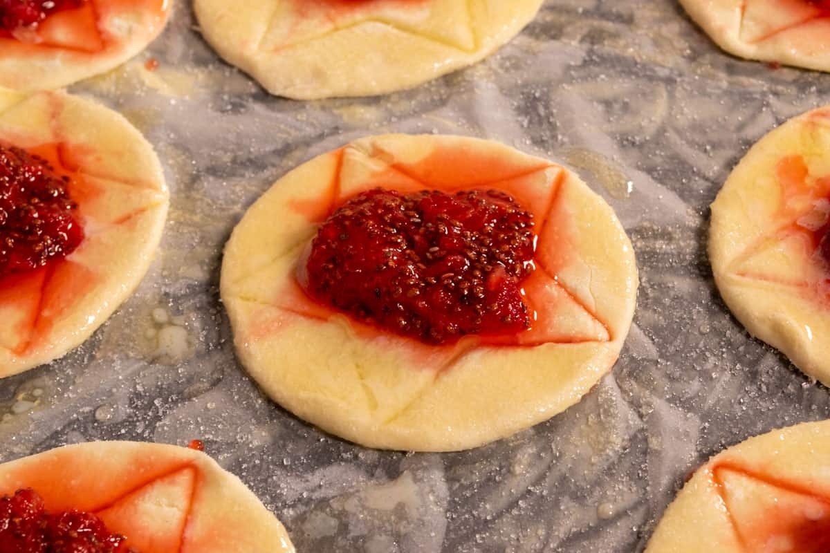 The unbaked pastry has had jam added to the centers and has been brushed with the vegan 'egg' wash mixture.