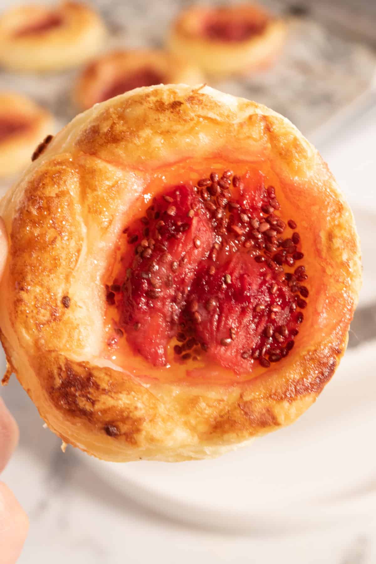A golden, undecorated pastry which is filled with lots of jam.
