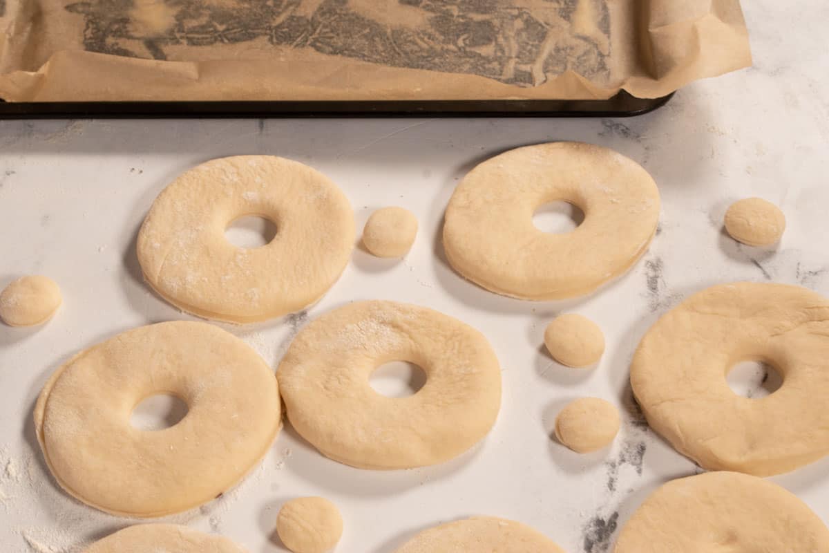 The rolled dough has been cut out into donut shapes. 