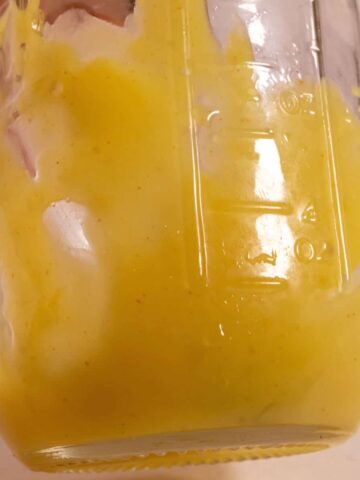 Vegan lemon curd inside a meson jar. It is dripping down the sides.
