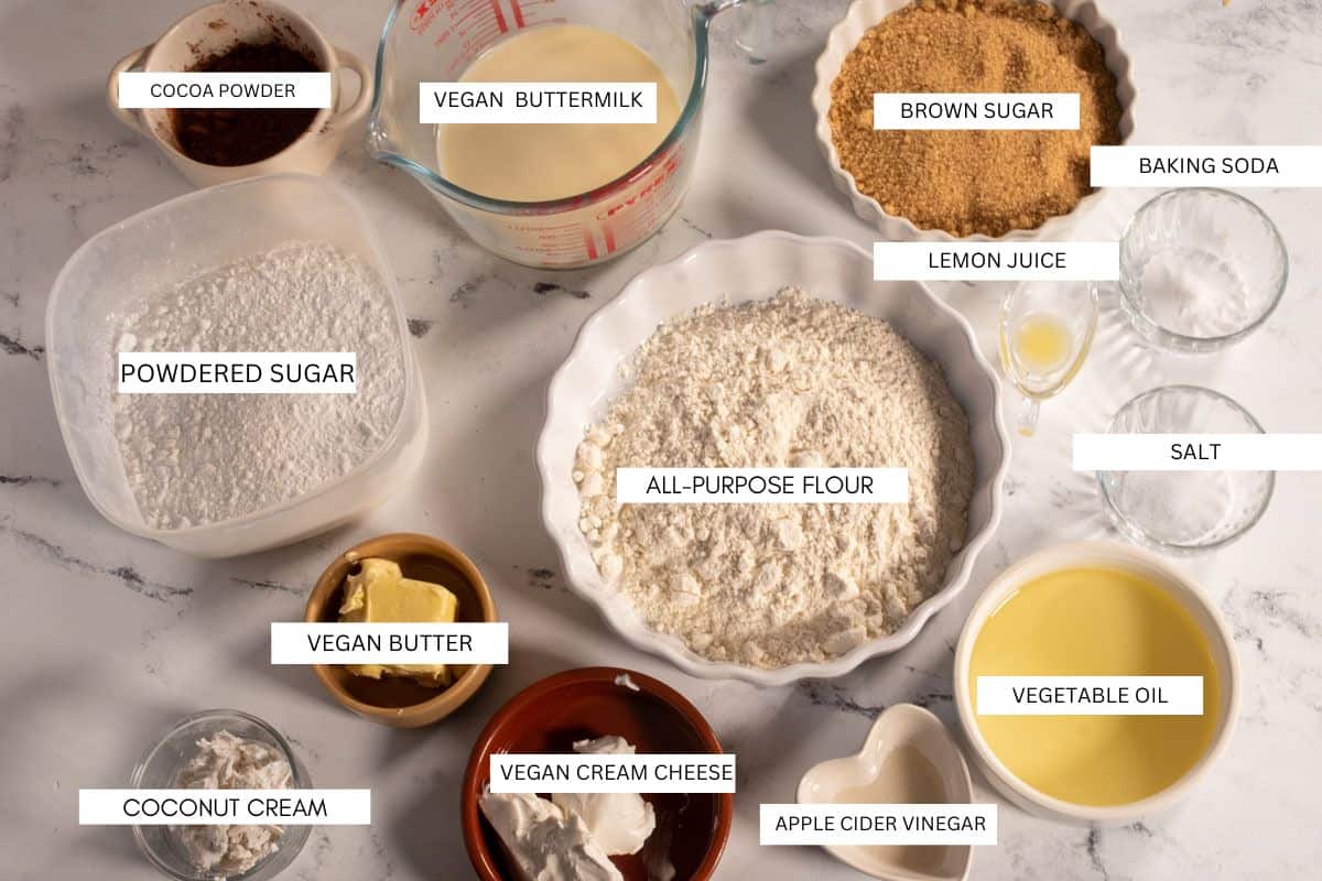 The ingredients that you will need in order to make vegan mascarpone chocolate sheet cake bars laid out over a white, marble background.