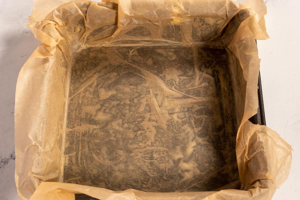 A square baking pan lined with parchment paper.