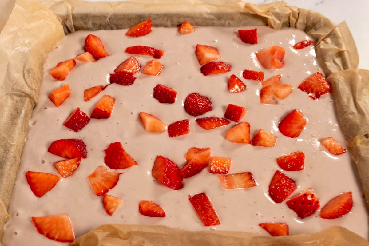 The cheesecake filling has been made and poured over the crust. It has also been topped with the fresh strawberries.